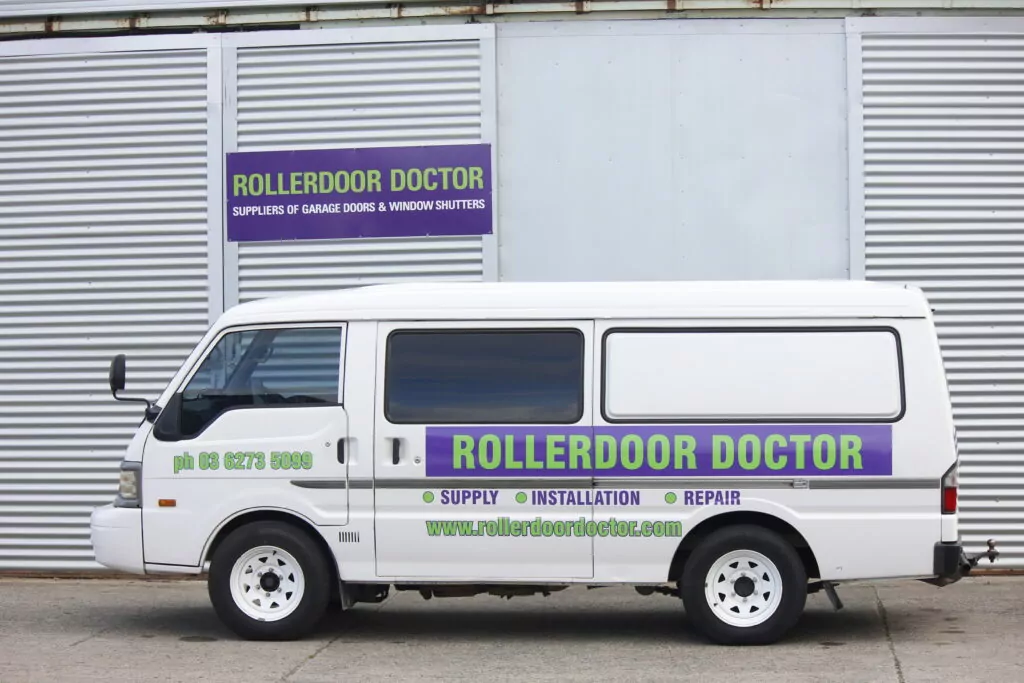 Photo of a white van with roller door doctor branding on it.